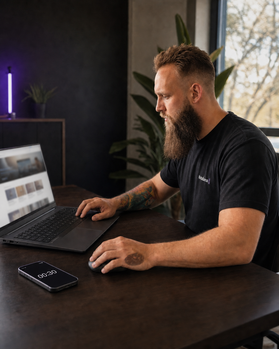 Rafael Hager prüft konzentriert eine unscharf dargestellte Karriereseite am Laptop. Sein rechter Unterarm trägt den farbigen Sleeve, auf dem linken Handrücken sitzt eine Pfote. Daneben läuft auf einem Smartphone ein 30-Sekunden-Timer.